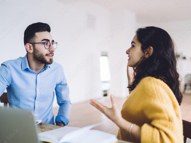 Jeune femme et trentenaire discutant autour d'un ordinateur.